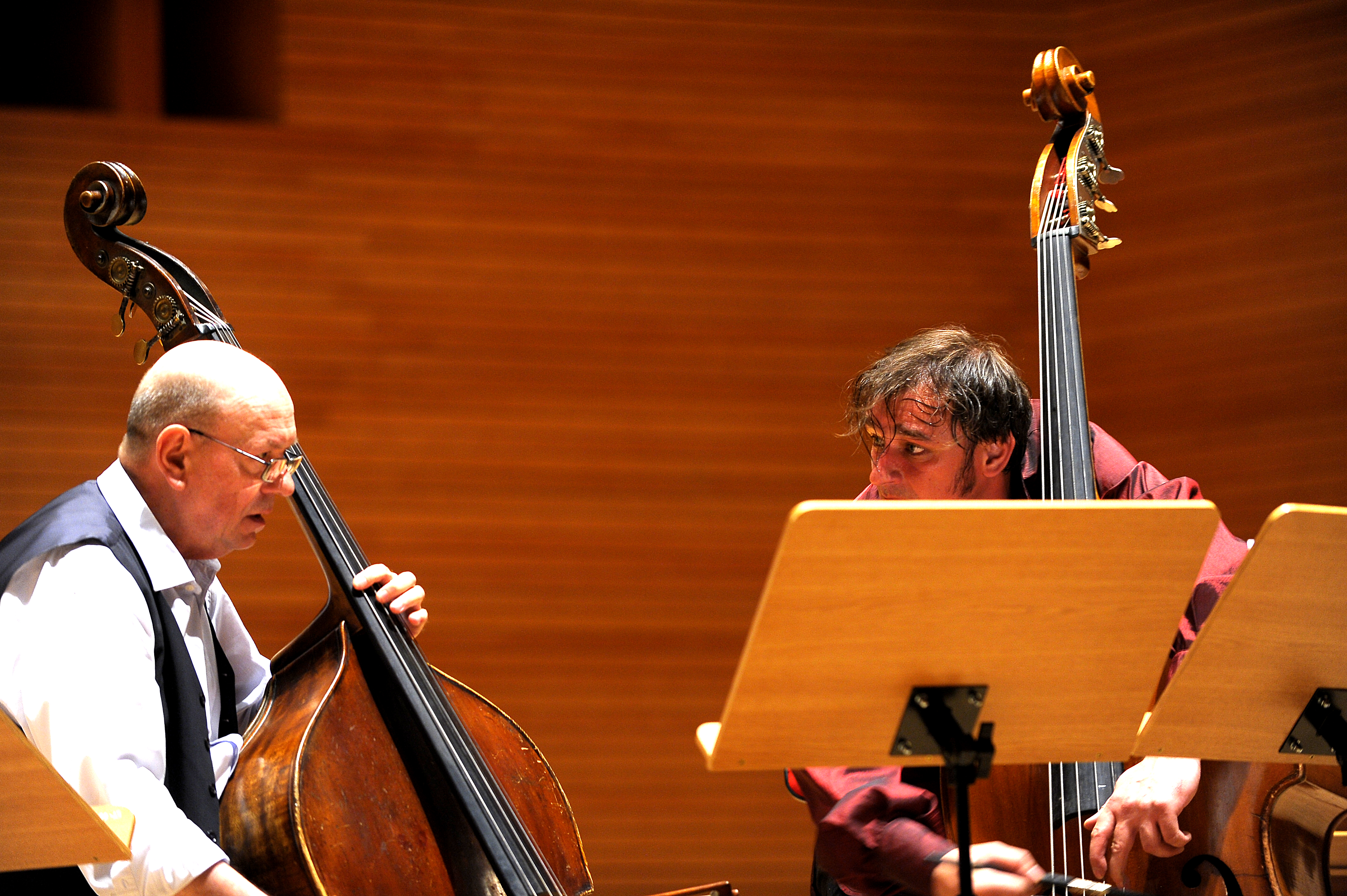 Zbigniew Wegehaupt and Aleksander Gabryś playing double basses and looking towards one another across the music stands.